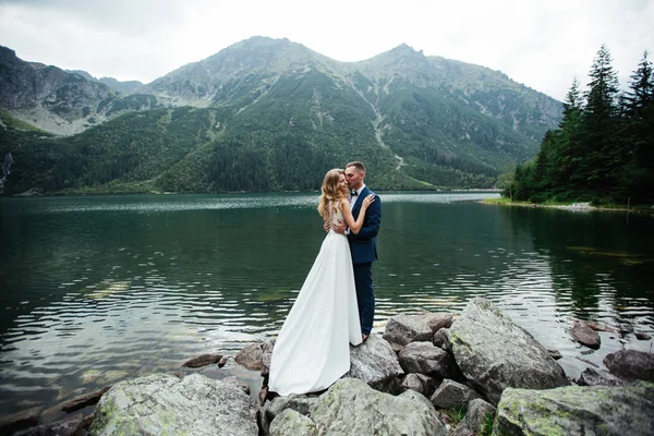 Noiva e noivo no dia do casamento andando ao ar livre na natureza de primavera. Casal nupcial, mulher recém-casada feliz e homem abraçando no parque verde. Casal de amor ao ar livre. Noiva e noivo — Fotografia de Stock