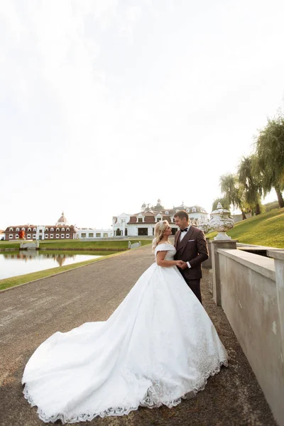 Bruid en bruidegom op huwelijksdag buiten lopen op lente aard. bruidspaar, gelukkig jonggehuwde vrouw en man omarmen in groen park. liefdevolle bruidspaar buiten. — Stockfoto