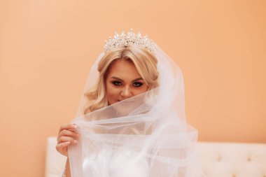 Gelin peçesini elinde tutuyor.