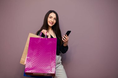 Güzel, iyi giyimli genç bir kız elinde boş bir kese kağıdıyla bir online mağazada arka planda metin veya tasarım için fotokopi alanı olan bir mağazaya bakıyor. Yatay yerleşim.