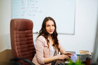 Gülümseyen güzel bir iş kadını. Uzun saçlı, kahverengi saçlı bir kadın. Bir ofis sandalyesinde oturmuş kariyerinin gelişmesini bekliyor..