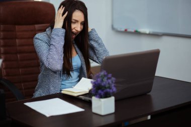 Dizüstü bilgisayarın başında oturan kızgın kadın..