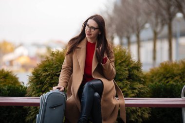 Gülümseyen başarılı iş adamının uzun bir portresi havaalanında bavulu çekiyor..