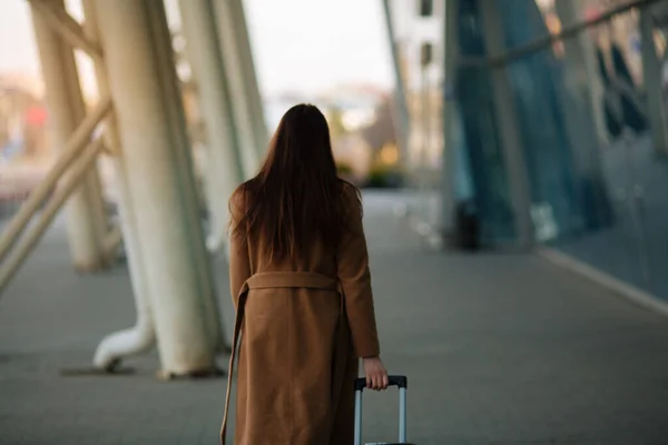 Full body side portrait of business woman walking with suitcase in terminal.