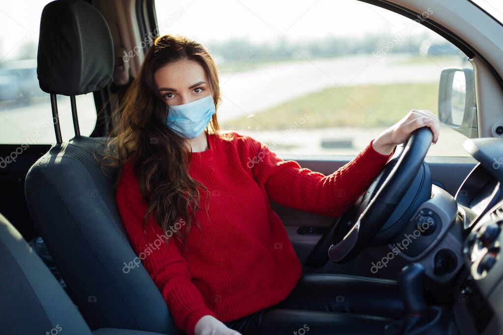 young woman in coronavirus mask sitting in car.