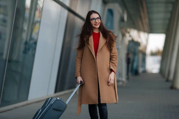 Full body side portrait of business woman walking with suitcase in terminal.