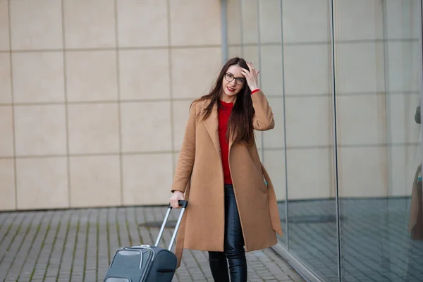 Young beautiful business woman suitcase in urban setting.