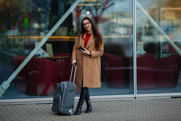 Young beautiful business woman suitcase in urban setting.