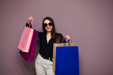 Mutlu Avrupalı güzel bir kızın portresi. Elinde alışveriş çantaları var. Arka planda soyutlanmış görünüyor. Renkli bir alışveriş anlayışı.