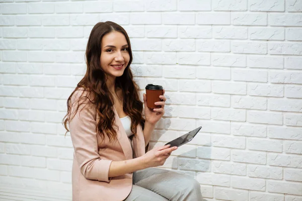 Portrait of happy businesswoman holding digital tablet in office, drinking coffee.