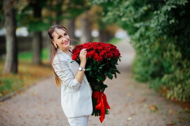 Sevgililer Günü 'nün 101. Doğum günü hediyesi. Güzel makyajlı güzel bir kadın. Elinde kocaman bir buket gül tutan bir kız. Mükemmel şehvetli dudaklar. Moda makyajı. Küpeli kadın..