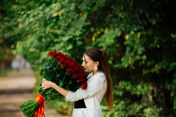 何百本もの赤いバラの花束を保持エレガントなスーツでファッショナブルな豪華なセクシーな女の子 ハッピーバレンタインデー — ストック写真