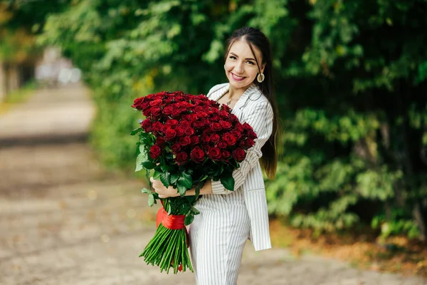 バレンタインデー101誕生日ギフトあなたのために スタイリッシュなメイクの女性 バラの豪華な大きな花束を持っている女の子 完璧な官能的な唇 ファッションメイク イヤリングの女 — ストック写真