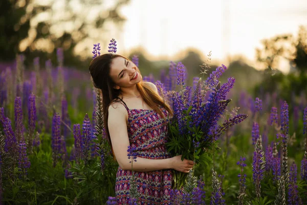 brunette in a flower field.The girl holds lupines purple.