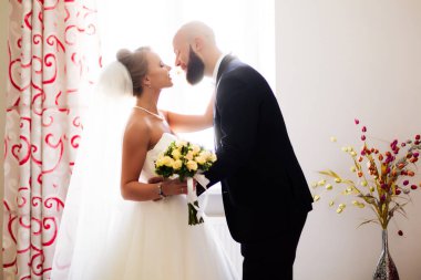 Genç gelin ve damat, arka planda kucaklaşıyorlar.