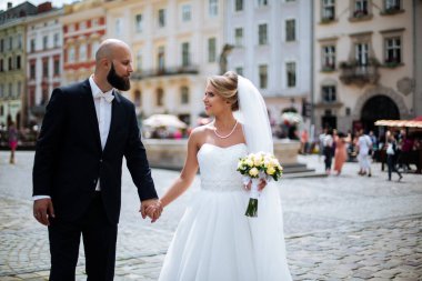 Muhteşem bir düğün çifti, eski şehirde mimari ile güneşli bir günün tadını çıkarıyor..