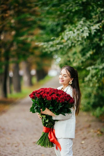 バレンタインデー101誕生日ギフトあなたのために スタイリッシュなメイクの女性 バラの豪華な大きな花束を持っている女の子 完璧な官能的な唇 ファッションメイク イヤリングの女 — ストック写真