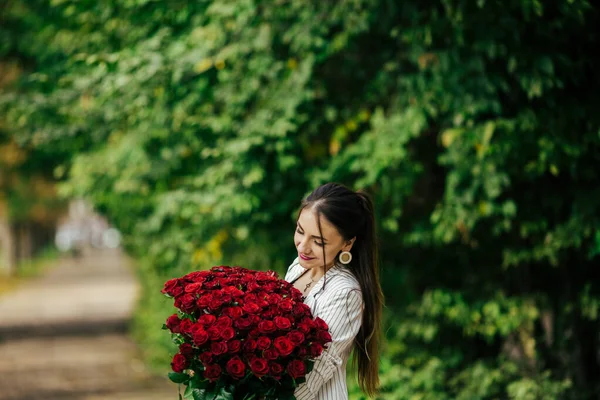 バレンタインデー101誕生日ギフトあなたのために スタイリッシュなメイクの女性 バラの豪華な大きな花束を持っている女の子 完璧な官能的な唇 ファッションメイク イヤリングの女 — ストック写真