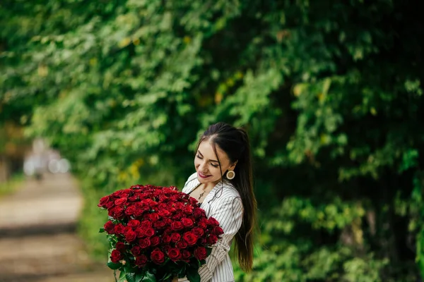 緑の背景にバラの手に花とスーツの美しい女の子 — ストック写真