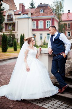 Gelin ve damat parkta birlikte yürürler. Beyaz elbiseli çekici gelin, damat koyu renkli şık bir takım giyiyor.