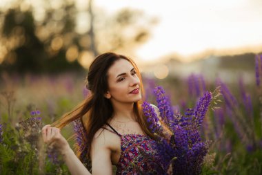Genç ve güzel bir esmerin açık hava portresi. Çiçeklerle dolu bir tarlada çekici seksi bir kız..