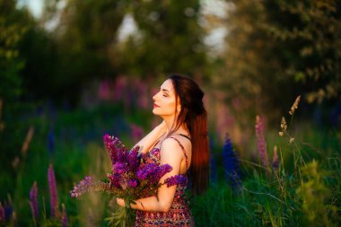 Genç kız lavanta tarlasına bakan alanda duruyor. Gülümseyen kaygısız beyaz kız günbatımının tadını çıkarıyor..