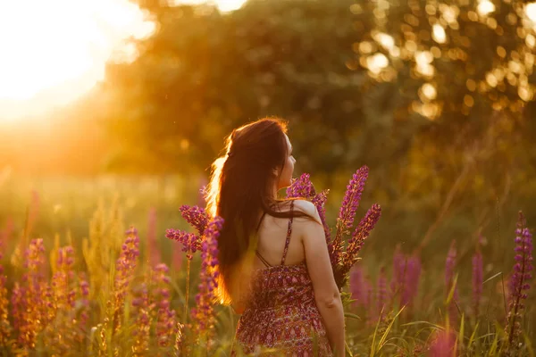 夕暮れ時に畑にいた若い女性 花を持つ — ストック写真