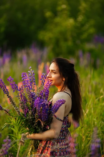 Young girl stand in field overlooking lavender field. Smiling carefree caucasian girl in dress enjoying the sunset.