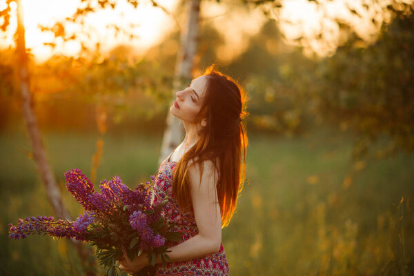 Girl holding flowers. Brunette in field. sunset.