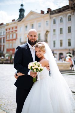 Muhteşem bir düğün çifti, eski şehirde mimari ile güneşli bir günün tadını çıkarıyor..