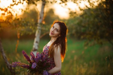 Çiçek tarlasında esmer. Kız lupinleri mor tutuyor..