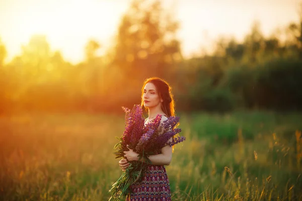 女の子は花を持ってる 畑の中のブルネット — ストック写真