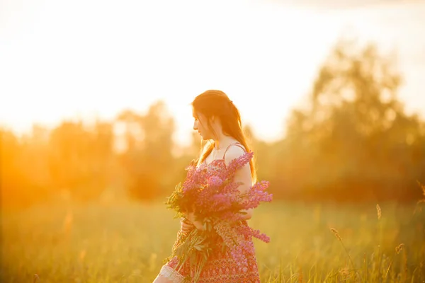日落时 一个漂亮的年轻女子在田野里 抱着花 — 图库照片