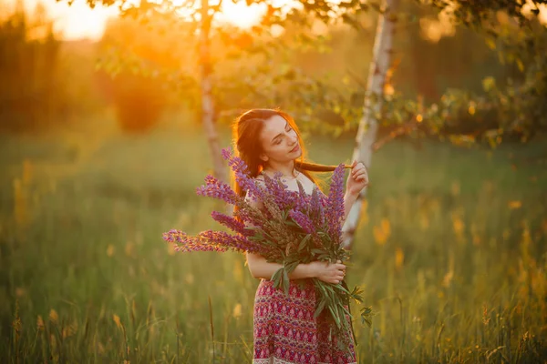 Young girl stand in field overlooking lavender field. Smiling carefree caucasian girl in dress enjoying the sunset.