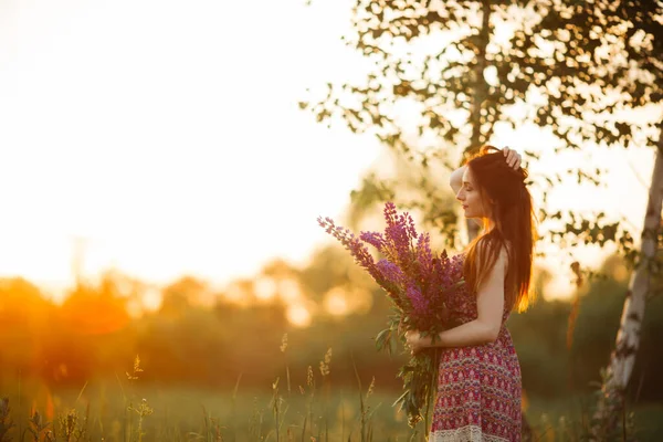 夕暮れ時に畑にいた若い女性 花を持つ — ストック写真