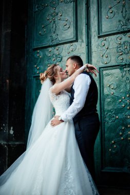 Gelin ve damat parkta birlikte yürürler. Beyaz elbiseli çekici gelin, damat koyu renkli şık bir takım giyiyor.