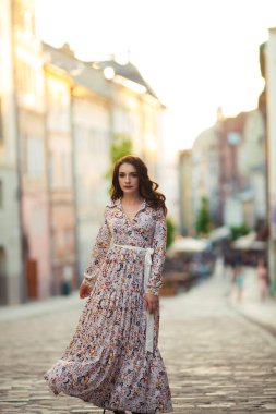 Esmer kadın, Lviv sokaklarında uzun ve güzel bir elbiseyle yürüyor..