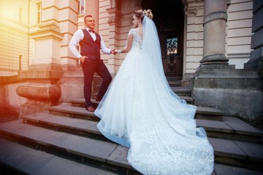 Gelin ve damat parkta birlikte yürürler. Beyaz elbiseli çekici gelin, damat koyu renkli şık bir takım giyiyor.