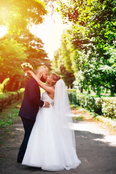 一位年轻漂亮的新娘和她的丈夫站在一个夏季的公园里 手里拿着一束鲜花 — 图库照片