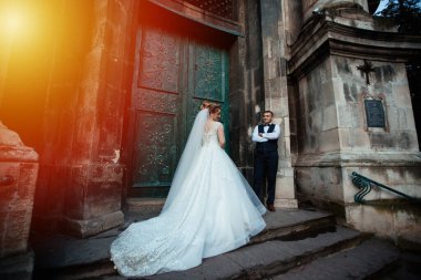 Gelin ve damat parkta birlikte yürürler. Beyaz elbiseli çekici gelin, damat koyu renkli şık bir takım giyiyor.