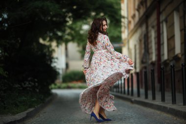 Esmer kadın, Lviv sokaklarında uzun ve güzel bir elbiseyle yürüyor..