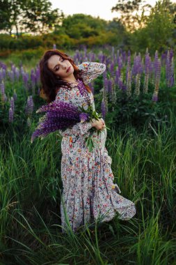Güzel esmer, elinde lupin çiçekleri, akşam makyajı.