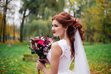 Parkta bir buket çiçekli gelin portresi, güneşli bir gün..