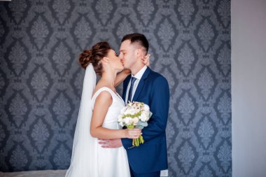 Aşık düğün çifti. Gelinlik buketi olan beyaz elbiseli güzel bir gelin ve evde duran mavi elbiseli yakışıklı bir damat..