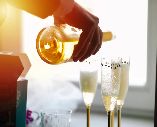 Pouring champagne in flutes standing on table.