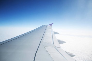 Gökyüzündeki bulutların üzerinde uçan uçağın kanatları.