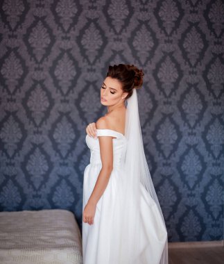 Göz kamaştırıcı makyajı ve saç stili olan güzel ve moda gelini. Güzel gelin evde zarif bir gelinlik deniyor..