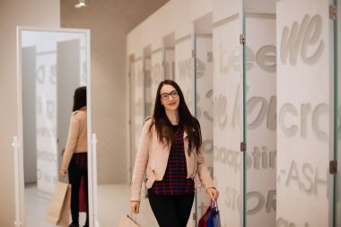 Alışveriş merkezinde elinde poşetlerle yürüyen güzel bir esmer..