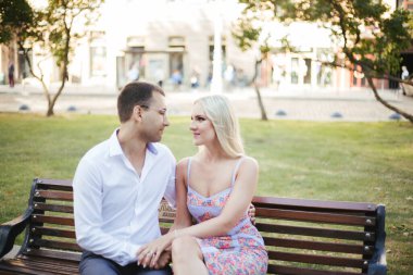 Mahallede dolaşan sevimli bir çift. Siyah saçlı, beyaz gömlekli, güzel elbiseli bir sarışına sarılan adam.