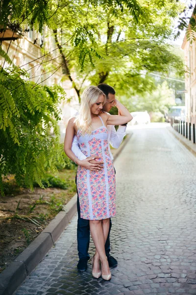 Mladý pár v lásce objetí navzájem na pozadí města — Stock fotografie